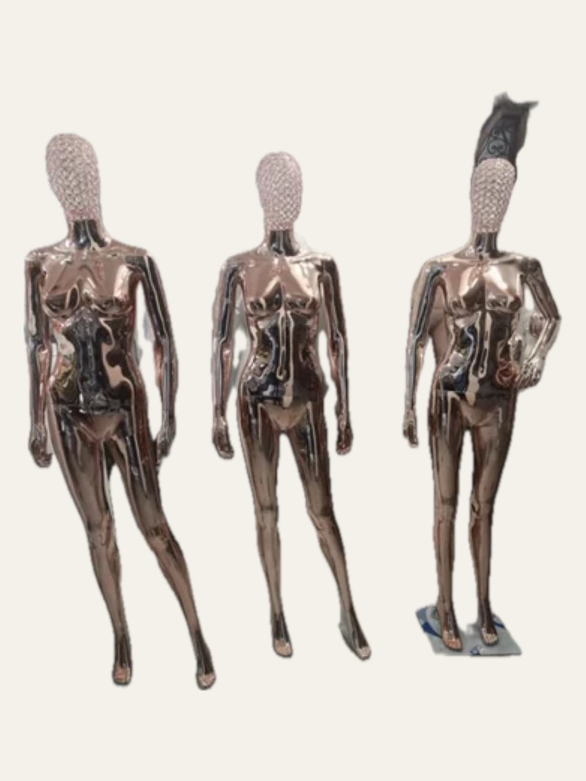 Three metallic-finish female mannequins with crystal-studded heads, side by side